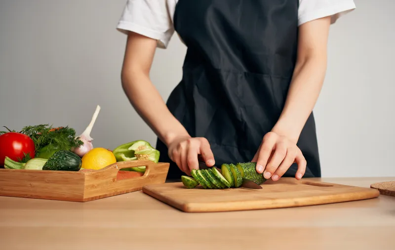 Приготовление здоровой пищи на кухне, чёрный фартук, нарезка овощей