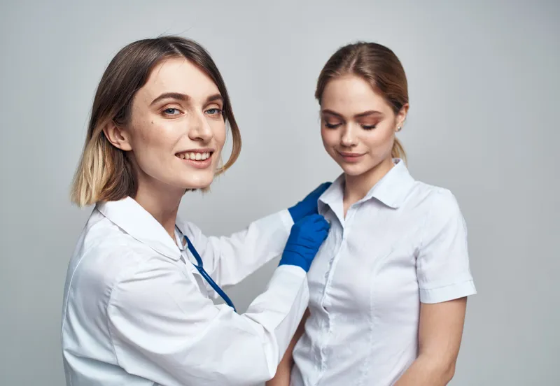 Счастливая женщина-врач в синих перчатках и пациентка в белой футболке