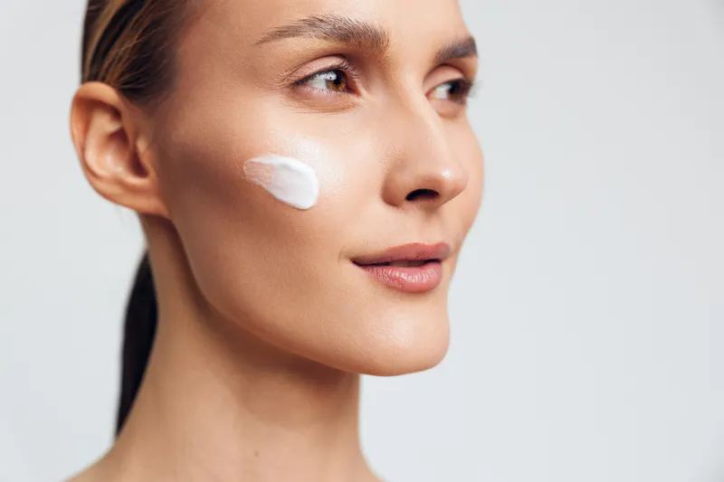 Woman closeup skincare beauty cream on face, gentle hydration care and therapy mood, bright studio light, clean background, demonstrating moisturizer application for glowing complexion