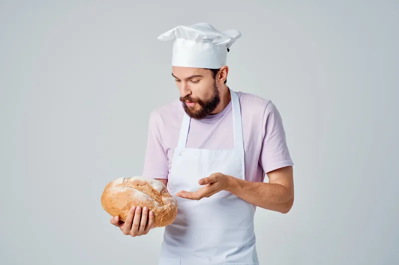 Весёлый пекарь-мужчина готовит еду на кухне ресторана