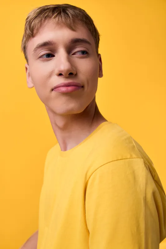 Male model in a bright yellow shirt against a yellow backdrop, showcasing casual style, relaxed pose, and confident expression for fashion and lifestyle campaigns