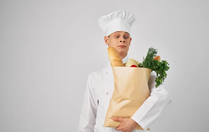 Шеф-повар с продуктами занимается приготовлением еды в ресторане, профессиональный образ жизни на сером фоне