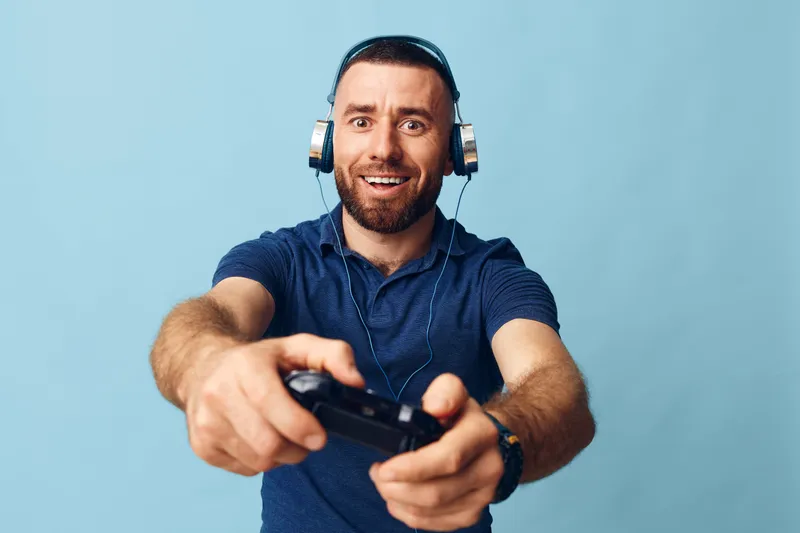 Взрослый мужчина держит игровой контроллер, увлечённо играет