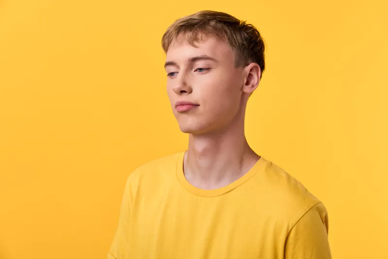 Yellow themed photo features a young man in a matching yellow tee, standing against a vibrant yellow backdrop, conveying calm confidence and minimalist fashion vibe, ideal for fashion, lifestyle or