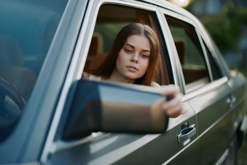 Young woman looking out of a car window, enjoying the scenic view with a relaxed expression. Perfect for travel and adventure themes.