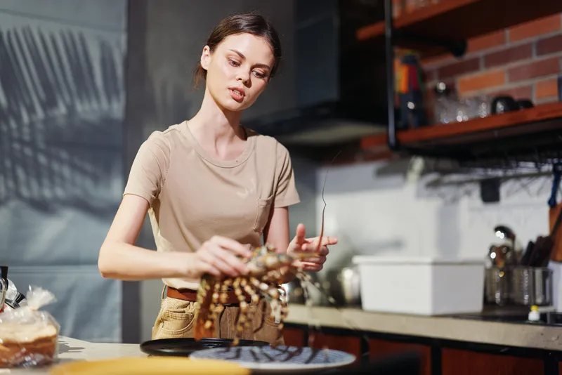 Женщина готовит на кухне, перед ней на тарелке лежит краб, она готовит вкусное блюдо из морепродуктов