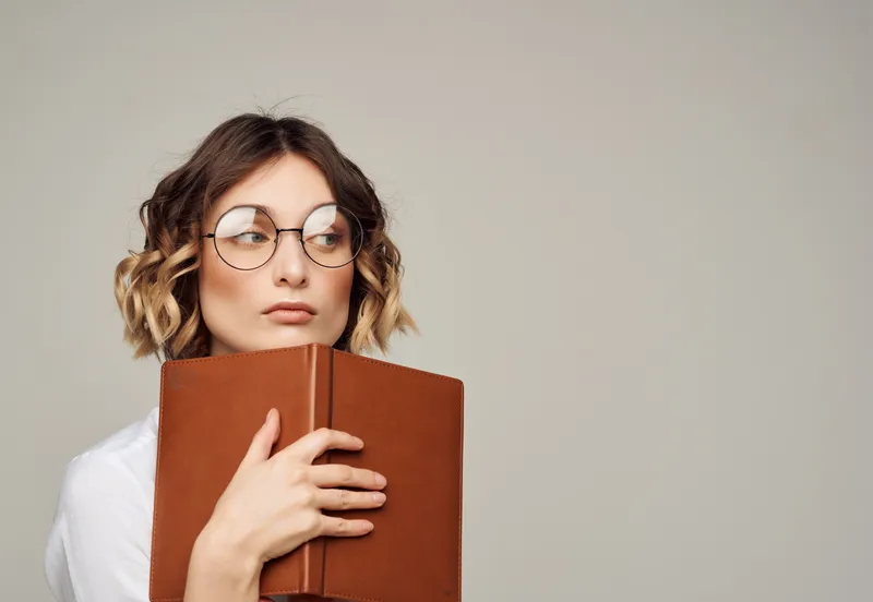 Женщина в очках с книгой в руках занимается официальной профессиональной работой