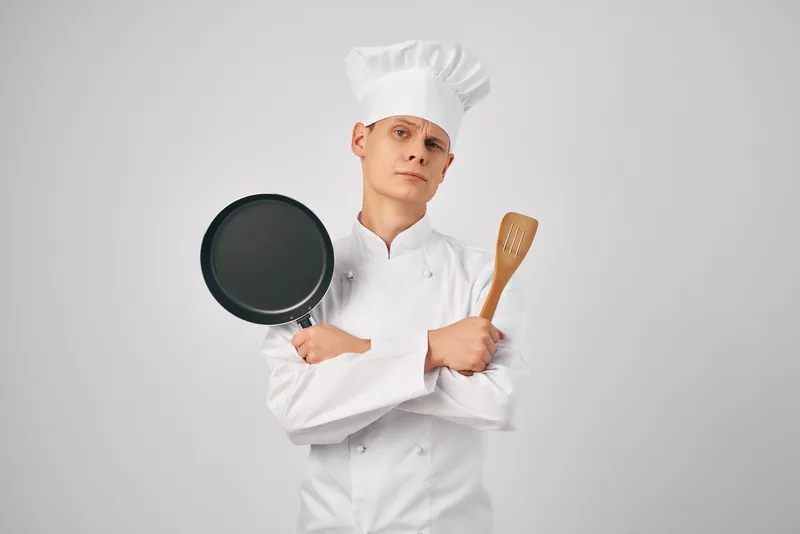 Мужчина в униформе шеф-повара профессионально занимается приготовлением пищи