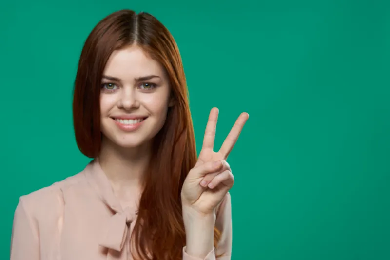 Симпатичная женщина показывает жест пальцем, привлекательно улыбаясь на изолированном фоне