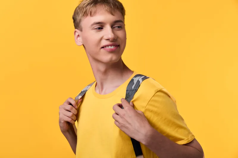 Backpack, student, casual, youth in a bright yellow setting, showing everyday optimism, readiness for learning, and new opportunities during a sunny journey and growth.