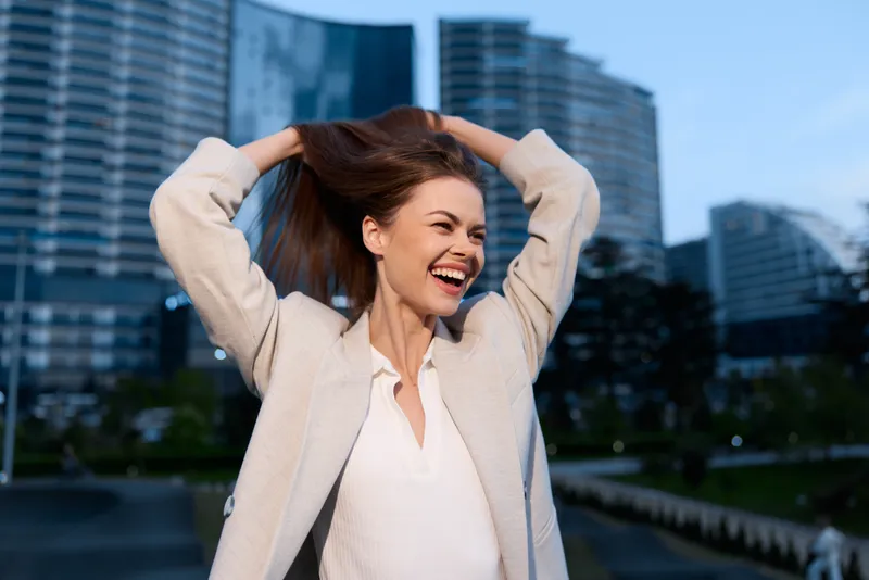 Happy woman in light jacket joyful outdoors urban background smiling natural emotions spring day fashion style
