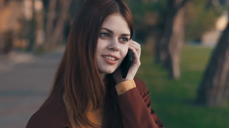 Симпатичная женщина на открытом воздухе разговаривает по телефону в парке
