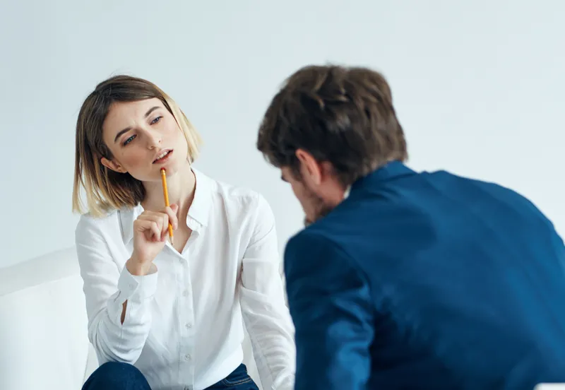 Мужчина и женщина, коллеги по работе, сидят на диване и разговаривают