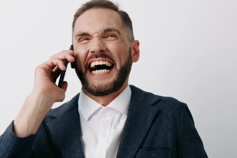 Businessman on a call, professional and confident, laughing with bright energy against a solid colored background, conveying positive mood and strong communication.