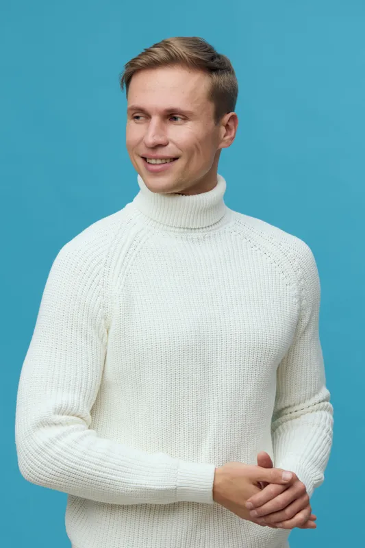 smiling young caucasian man in white turtleneck sweater look aside isolated on blue background happy emotion digital detox concept