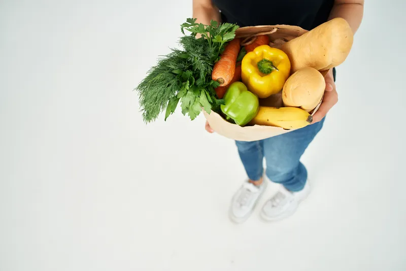 Пакет с продуктами и овощами на светлом фоне, напоминающем супермаркет