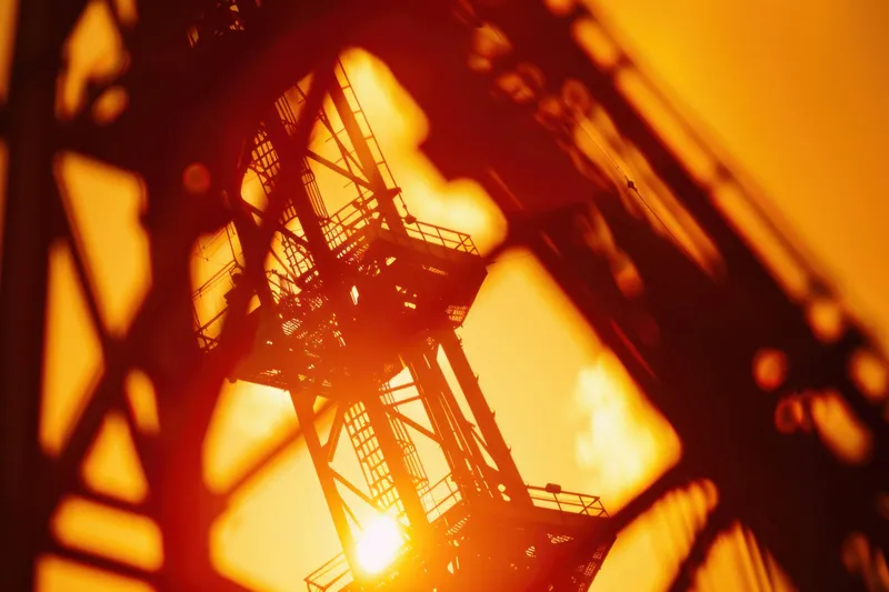 Крупный план металлического каркаса, silhouetted by a stunning sunset, подчеркивающий геометрические формы и теплые цвета