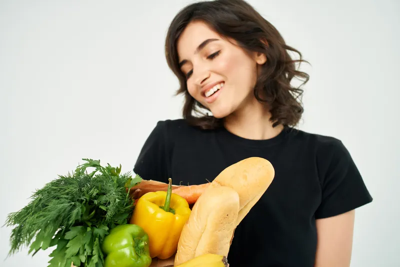 Женщина в черной футболке держит пакет с продуктами здорового питания