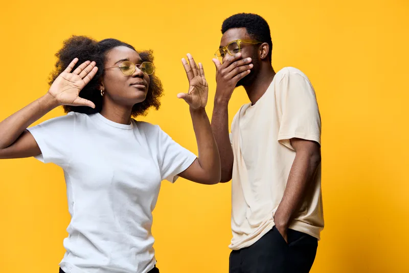 Young diverse couple having fun, playful expressions, wearing casual clothing against a bright yellow background, perfect for lifestyle themes and social interactions