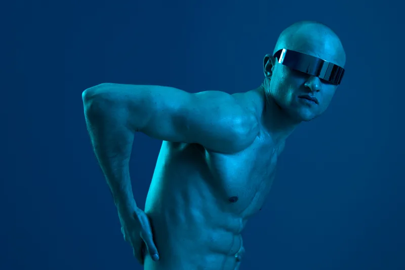 Athletic man posing confidently in a futuristic style, wearing sunglasses against a vibrant blue background. The image captures strength and modernity.