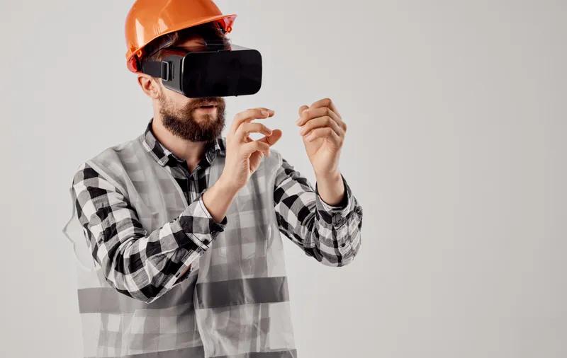 Инженер-строитель в оранжевой каске и 3D-очках на светлом фоне