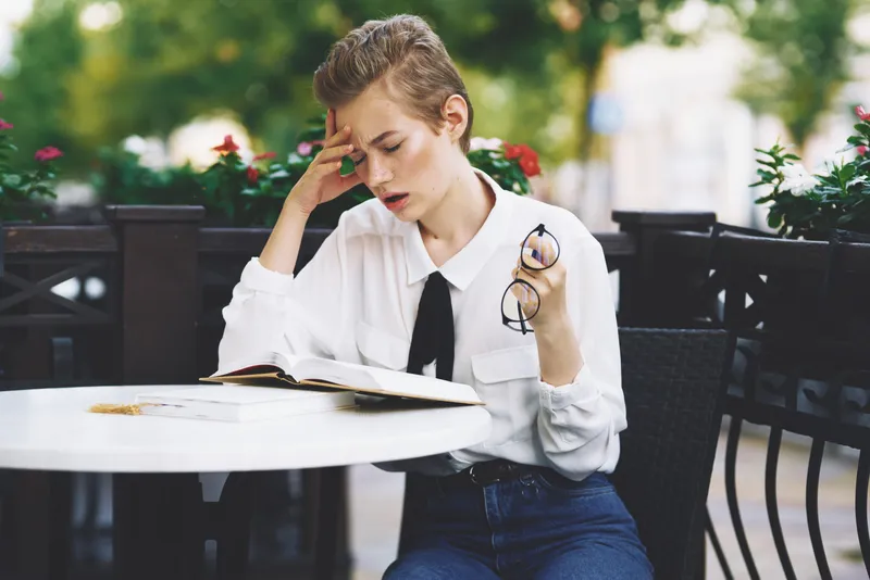 Женщина читает книгу за столиком в ресторане