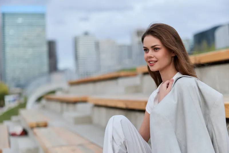 Confident woman in business attire outdoors, showcasing modern fashion with a vibrant urban background, emphasizing professionalism and elegance.