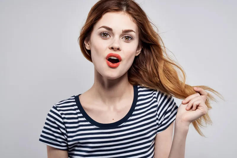 Симпатичная женщина в полосатой футболке делает жест руками, модель, студия