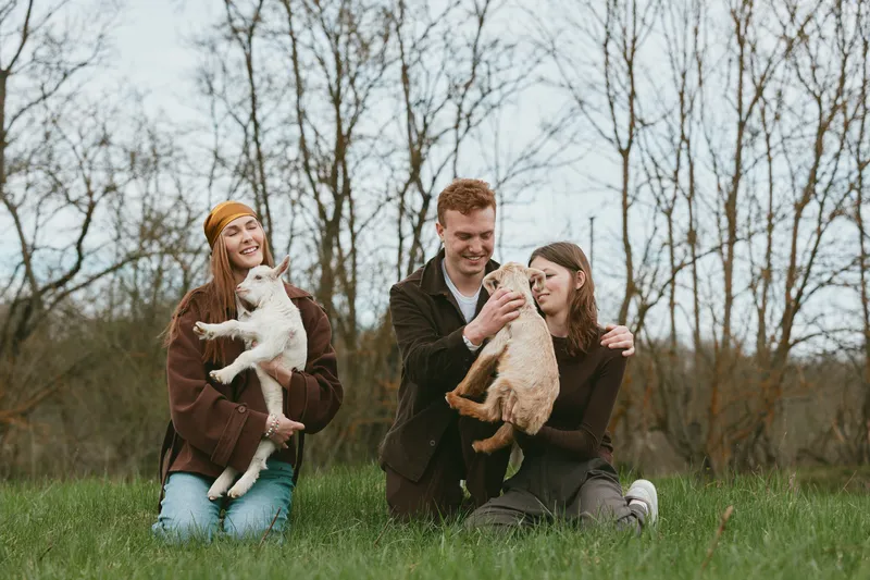 A cheerful family outdoors in a park with two dogs, enjoying playtime on a sunny day. Casual style, relaxed mood, and bonding moments capture a simple lifestyle with pets and friends.