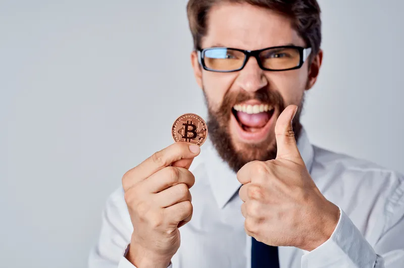 Весёлый мужчина с золотой монетой Bitcoin, криптовалюта, финансы