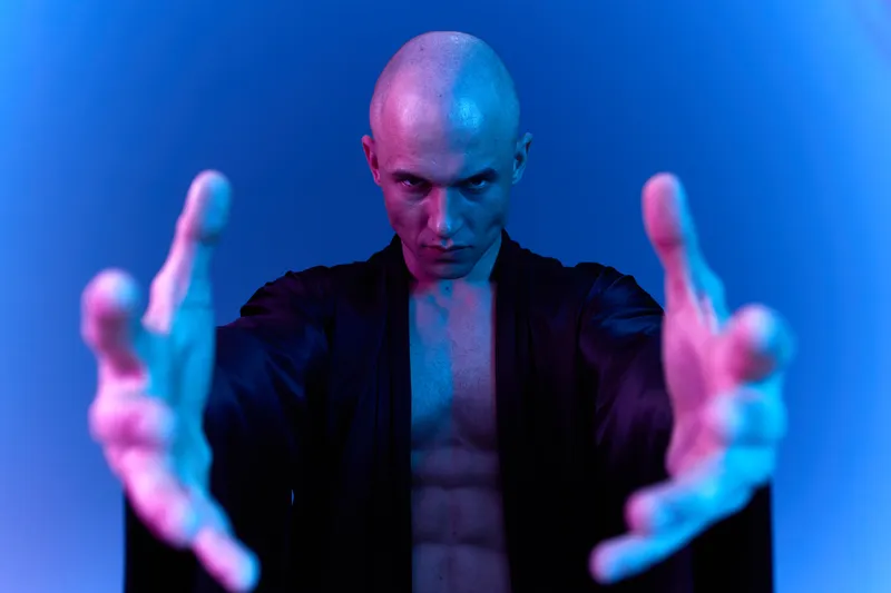 Intense man extending his arms, showcasing strength and determination. The image captures a dramatic color light composition that enhances the subject's presence.