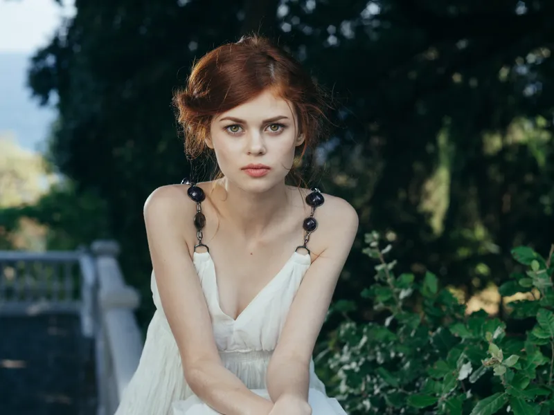 На фотографии запечатлена красивая женщина в белом платье на фоне природы