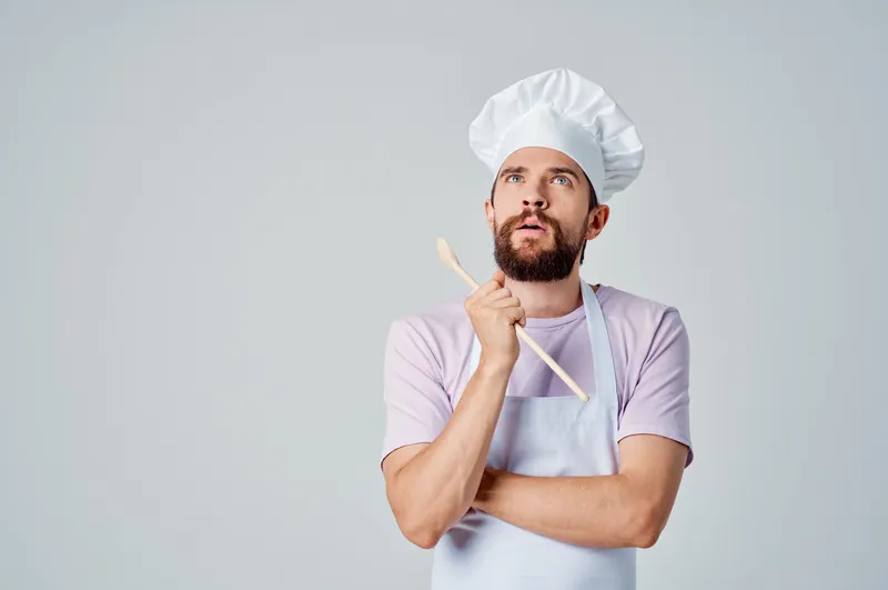 Профессиональный шеф-повар с деревянной ложкой в руке работает на кухне