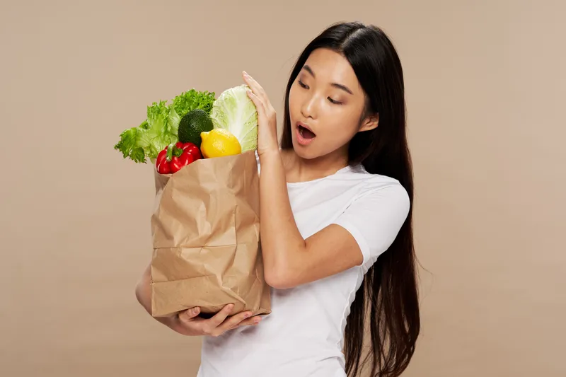 Женщина с пакетом продуктов здорового питания, закуски, бежевый фон, домохозяйка