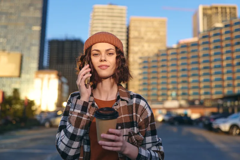 Woman with coffee and phone in urban morning, candid authenticity and golden hour glow. Portrait captures mindful living, relaxed style and emotional storytelling on city streets.