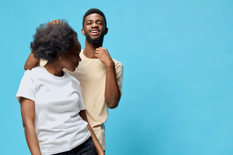 Stylish young couple having fun against a blue background, showcasing natural hairstyles and expressive emotions, perfect for themes of joy and relationships