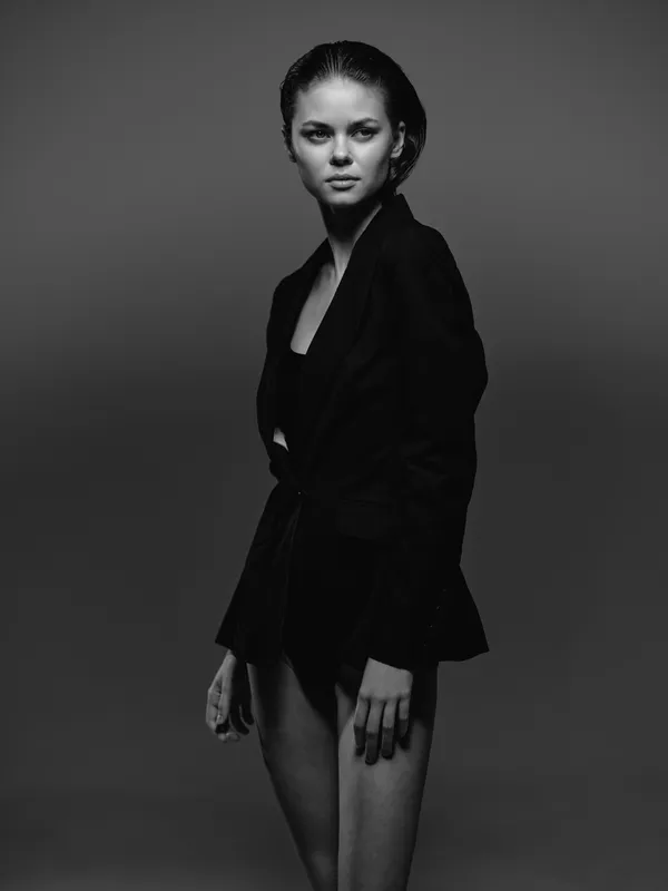 Black and white portrait of a confident woman in stylish blazer with serious expression on dark background