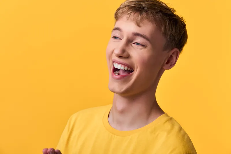 Joyful man in a yellow shirt smiles against a vibrant yellow backdrop, radiating positive energy, warmth and a friendly upbeat mood for lifestyle and marketing visuals