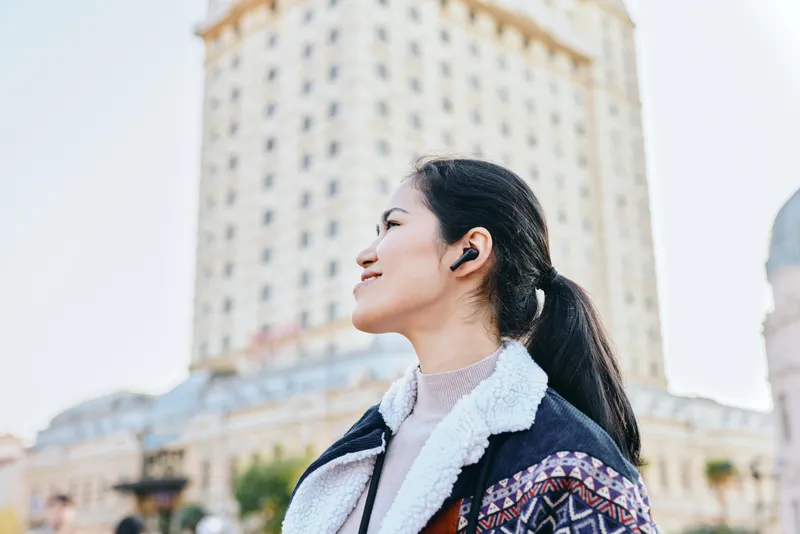 Headphones, woman and city outdoors fashion listening in daylight captures urban lifestyle with jacket and fleece, a confident moment amid skyline and street scenes