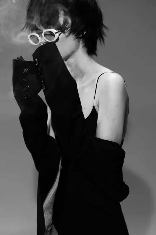 Black and white portrait of stylish woman wearing sunglasses and dark clothing with mysterious vibe