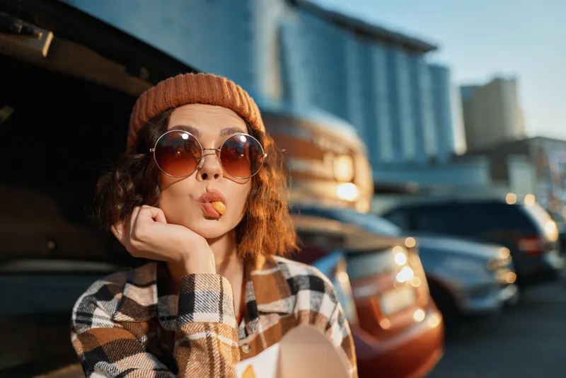 woman portrait candid golden sunglasses beanie car smile urban playful scene at golden hour with authenticity, candid lifestyle, golden hour glow, mindful living and emotional storytelling warmth