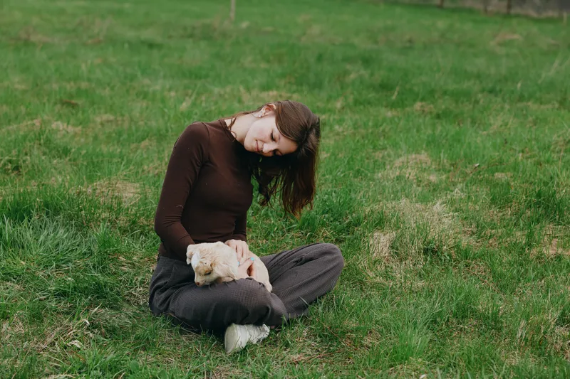 Woman outdoor grass pet serene relaxation nature countryside casual clothing sunlit moment portrait lifestyle tranquil gentleness breeze meadow mood