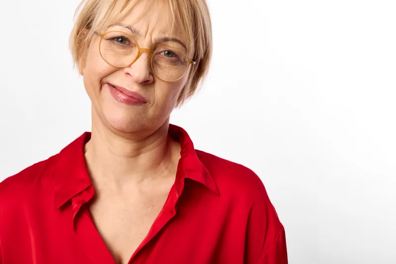 Woman portrait, glasses, smile, elderly, red, studio, white, headshot, calm, older woman in red shirt, studio lighting, soft focus, neutral background
