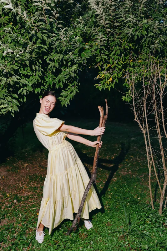 Woman yellow dress outdoors smiling with sticks authenticity inclusivity,