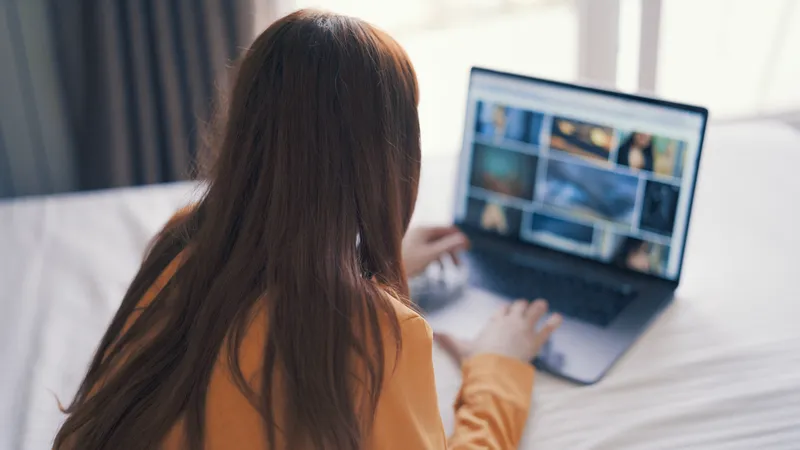 Женщина лежит в кровати перед ноутбуком, работая из дома через интернет