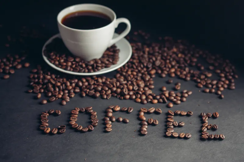 Чашка кофе на завтрак и надпись «arabica drink» на столе