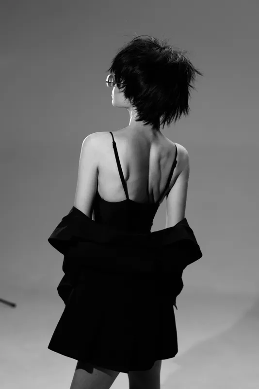 Black and white artistic portrait of a woman with short hair wearing a black dress, showcasing elegant style and mysterious mood.