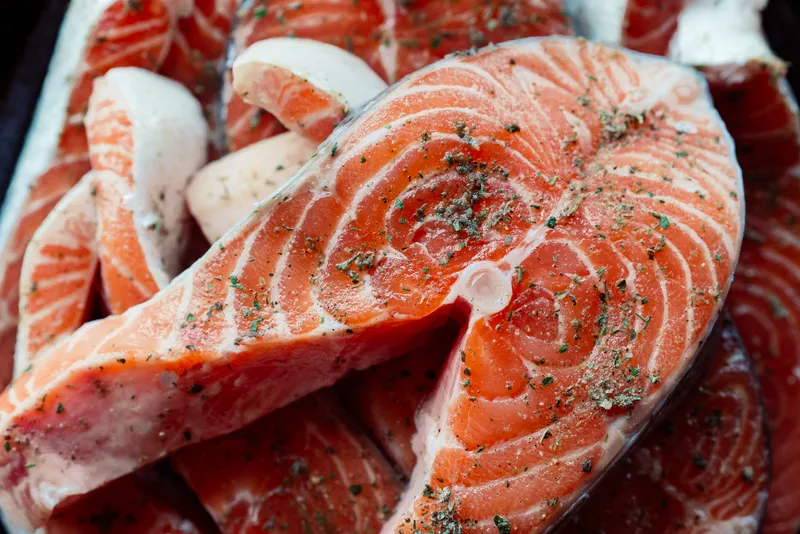 Маринованная красная рыба на тарелке, приготовление морепродуктов, деликатес