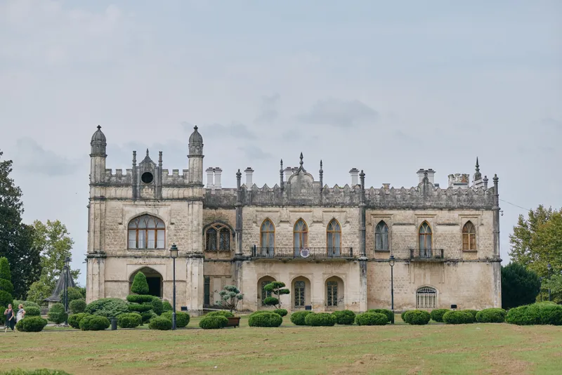 Mansion manor historic architecture stone facade estate landscape with detailed windows and turrets isolated building on lawn under cloudy sky preserved exterior masonry