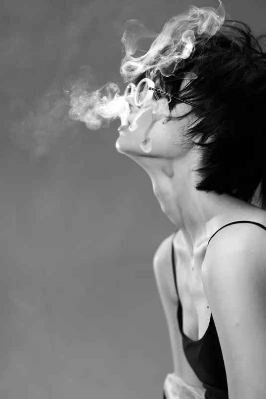 black and white woman smoking with smoke rings, artistic portrait, moody, stylish, short hair